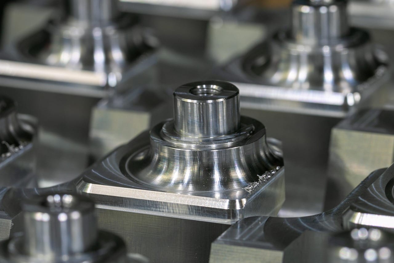 Nahaufnahme eines präzisions-gedrehten Metallteils mit gedrehten Absätzen und Gewindebohrung auf prismatischem Rohteil