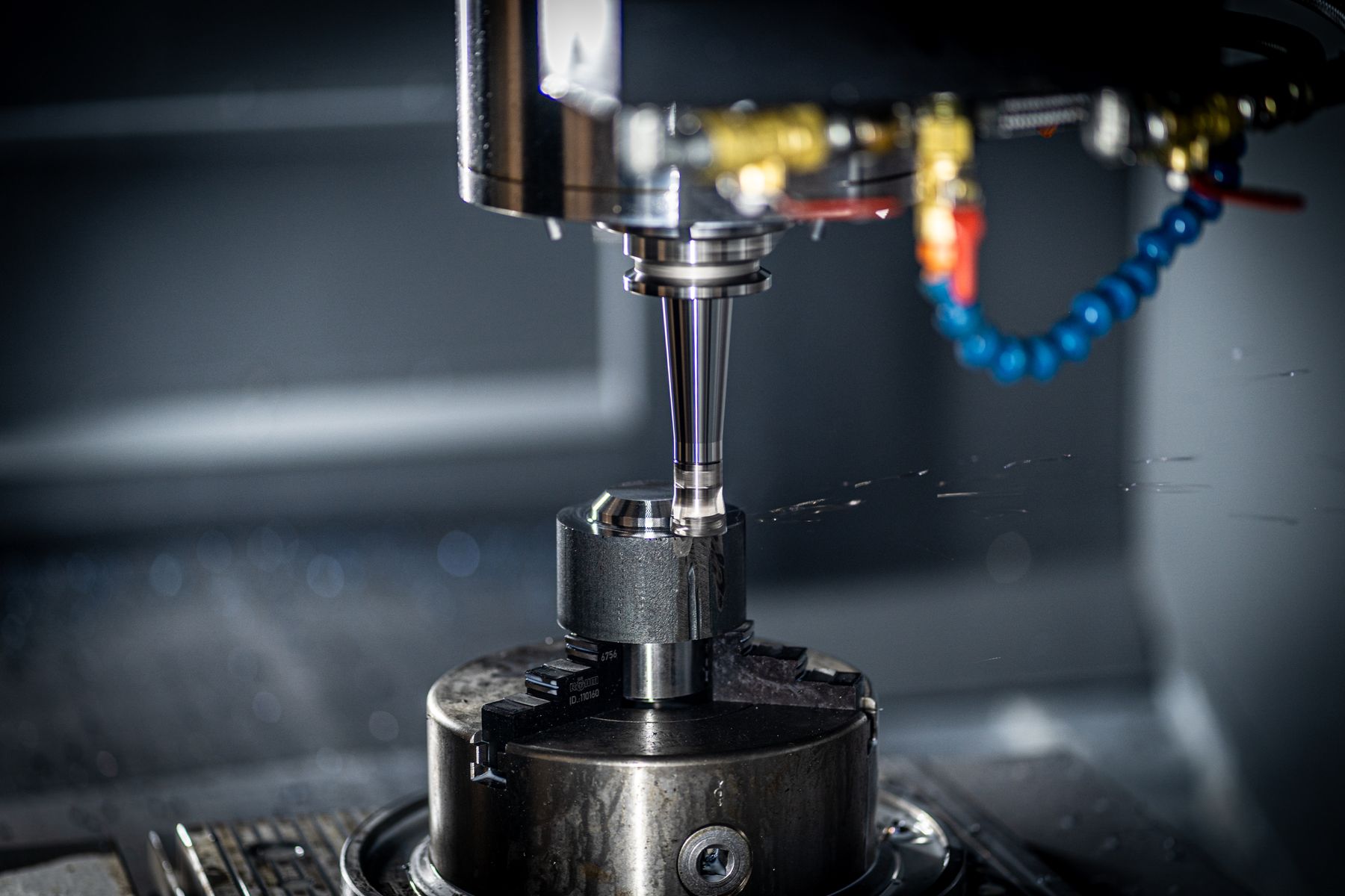 CNC-Bearbeitungszentrum mit Werkzeugspindel und Kühlmittelzuführung über einem gespannten Werkstück