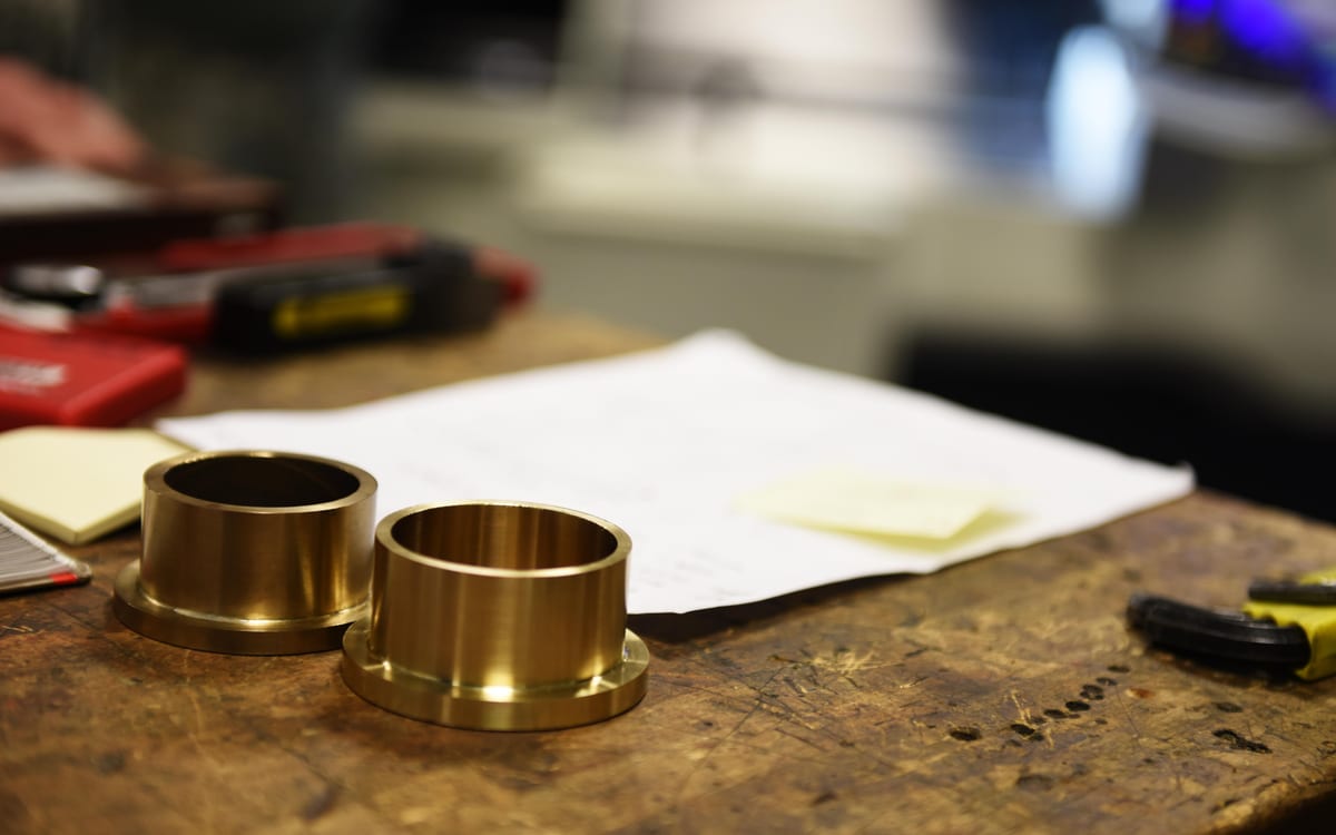 Zwei Messingbuchsen mit Flansch auf einer Werkbank in einer Metallwerkstatt